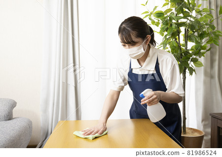 A woman's hand disinfecting the table with alcohol A woman's hand disinfecting the table with alcohol 81986524