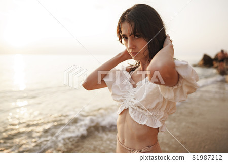 Portrait of young brunette haired woman at the beach at sunset 81987212