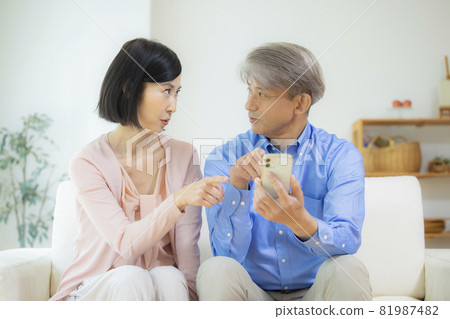 Middle couple watching smartphone together in the living room 81987482