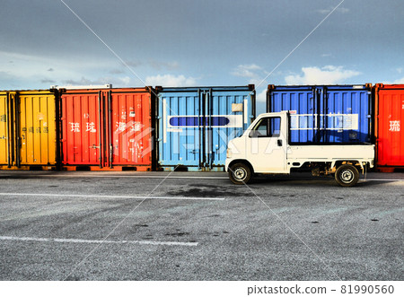 一輛白色輕型卡車停在港口碼頭的彩色貿易集裝箱前 81990560