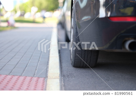 Car is parked near yellow median strip closeup Car is parked near yellow median strip closeup 81990561