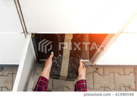Automated locker. Parcel courier box in woman hands at post delivery automat terminal. Courier Puts Cardboard Package Into Parcel Locker. 81990598
