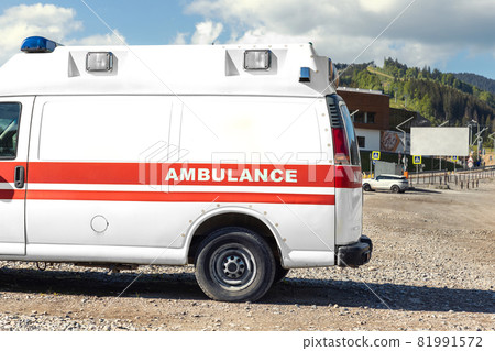Side view of white ambulance rescue ems van car parked near countryside rural road at highland mountain resort area. Paramedic first aid help service vehicle against alpine forest landscape 81991572