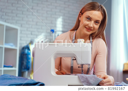 Cheerful young seamstress sitting at working table in her office 81992167