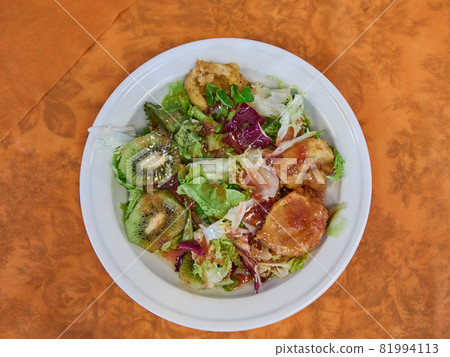 fresh salad with kiwi, lettuce and battered goat cheese on an orange background fresh salad with kiwi, lettuce and battered goat cheese on an orange background 81994113