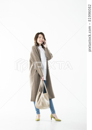 用智能手機打電話的年輕女子看著相機的白色背景 用智能手機打電話的年輕女子看著相機的白色背景 81996082
