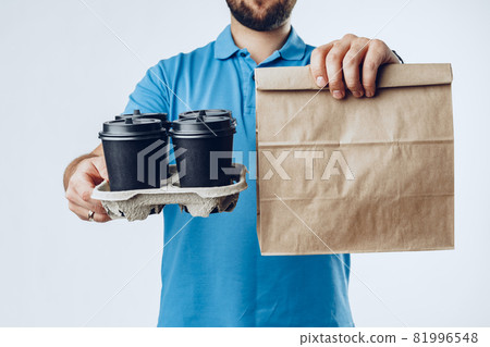Unrecognizable man in blue polo with food delivery orders against grey background Unrecognizable man in blue polo with food delivery orders against grey background 81996548