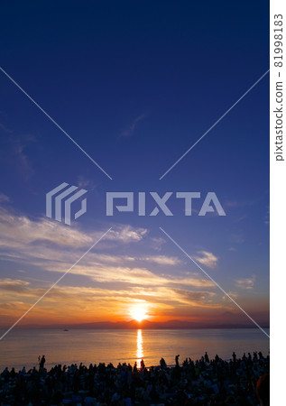 People are watching the beautiful sunset from the beach in Shonan. 81998183