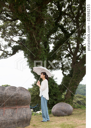 A woman standing by a big tree 81998255