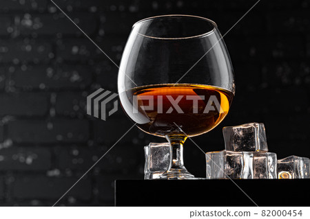 Whisky glass against dark black grunge wall 82000454