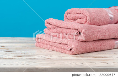 Stacked new towels on a wooden table Stacked new towels on a wooden table 82000617