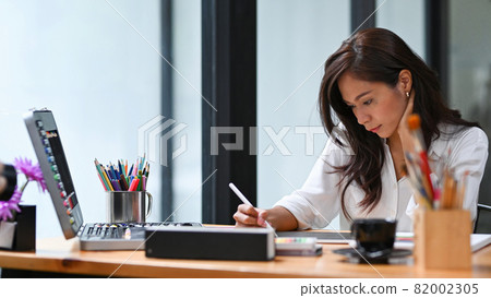 Beautiful creative woman working on new project with digital tablet in modern workplace. Beautiful creative woman working on new project with digital tablet in modern workplace. 82002305