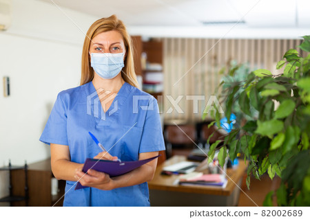 Female doctor in face mask standing in medical office 82002689