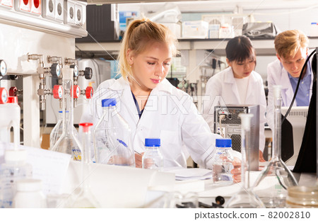 Female student writing report on chemical experiments 82002810