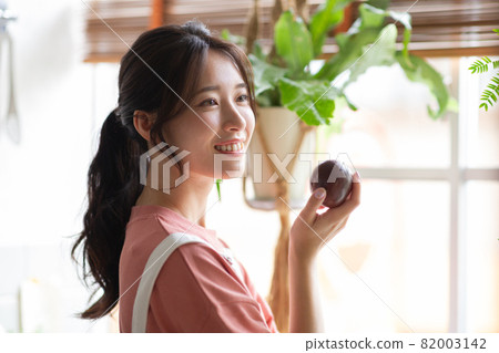 Cute lady with fruit in the kitchen Cute lady with fruit in the kitchen 82003142