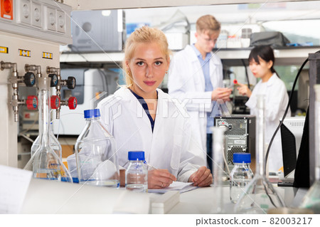 Female student writing report on chemical experiments 82003217