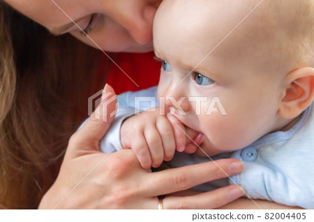 Little baby holding mother's finger in mouth. Little baby holding mother's finger in mouth. 82004405