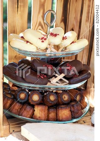 Vase with desserts. Cake pops in white and dark chocolate and cute cannele Vase with desserts. Cake pops in white and dark chocolate and cute cannele 82004412