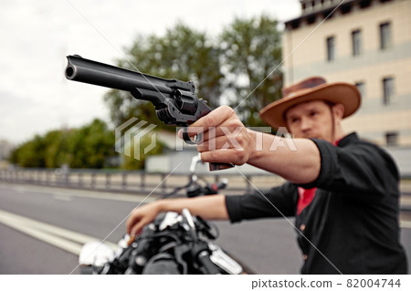 mafia man on bike with handgun. Sporty biker handsome rider male. Chase 82004744