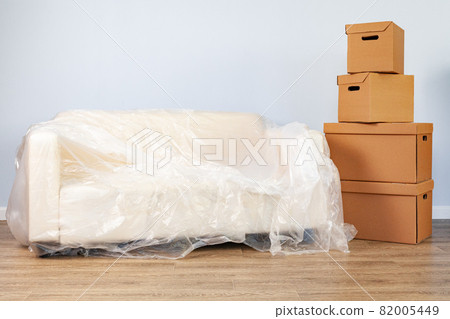 Packed household stuff in boxes and packed sofa for moving Packed household stuff in boxes and packed sofa for moving 82005449