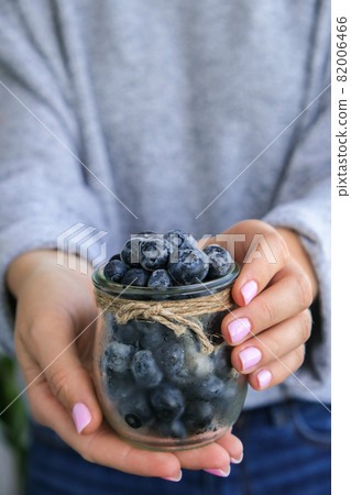 Woman holding bowl with Frozen blueberry fruits. Harvesting concept. Female hands collecting berries. Healthy eating concept. Stocking up berries for winter Vegetarian vegan food 82006466