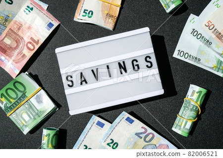 Lightbox board with word SAVINGS in black letters around Euro banknotes. Money, Business, finance, investment, saving Lightbox board with word SAVINGS in black letters around Euro banknotes. Money, Business, finance, investment, saving 82006521