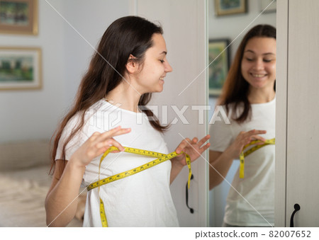 Woman measuring bust size using tape measure Woman measuring bust size using tape measure 82007652