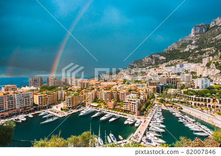 Yachts moored near city Pier, Jetty In Sunny Summer Day. Monaco, Monte Carlo architecture. Altered Sky With rainbow Yachts moored near city Pier, Jetty In Sunny Summer Day. Monaco, Monte Carlo architecture. Altered Sky With rainbow 82007846