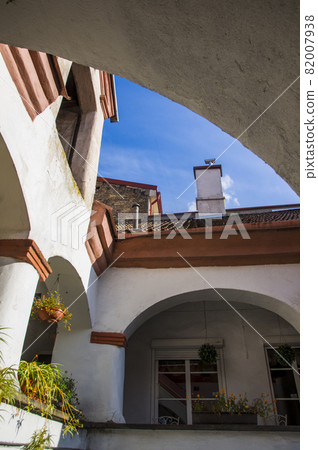 Abstract conceptual architecture of vintage roofs of houses with windows, balconies and oven and ventilation pipes against blue sky with clouds in old Town. Apartments in the attic against skyline 82007938