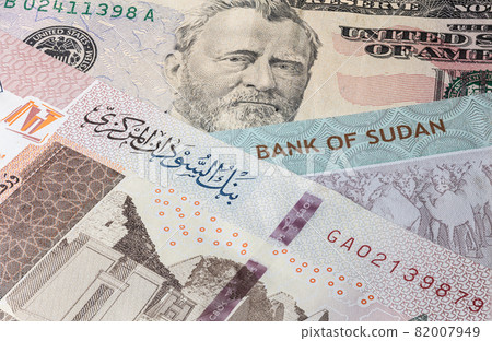 Close up to 100 Sudanese pounds of the Republic Sudan beside US dollars banknotes. 100 Pound banknotes of the African country Sudan. Money US with sudanese banknote. World currency. Hundred Pound 82007949