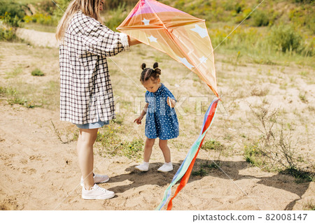 A charming little girl has fun and launches a kite together with her older sister 82008147