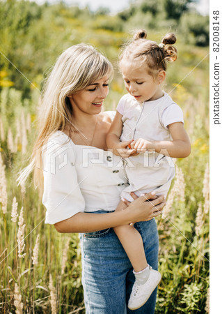 A young mother holds her little charming daughter in her arms 82008148