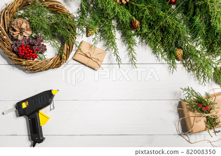 Make a Christmas wreath with your own hands. Spruce branch, Christmas wreath and gifts on a white wooden background Make a Christmas wreath with your own hands. Spruce branch, Christmas wreath and gifts on a white wooden background 82008350