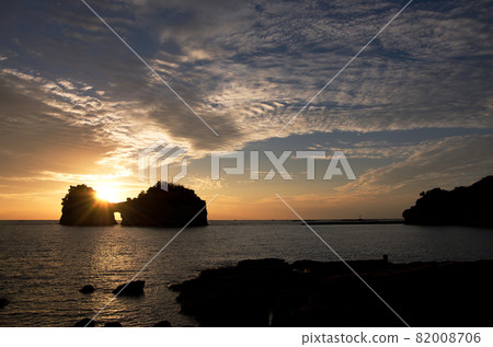 The sunset shines from the shadow of the island. The sky begins to dye the clouds orange, and the pattern with the blue sky is beautiful and you can feel the majesty. The sunset shines from the shadow of the island. The sky begins to dye the clouds orange, and the pattern with the blue sky is beautiful and you can feel the majesty. 82008706