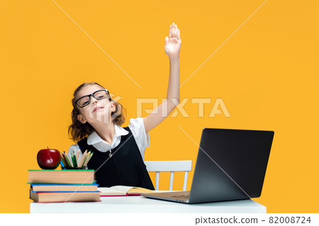 Caucasian schoolgirl raises hand up. Pupil sits at laptop during online lesson. Distant School Learning. Caucasian schoolgirl raises hand up. Pupil sits at laptop during online lesson. Distant School Learning. 82008724