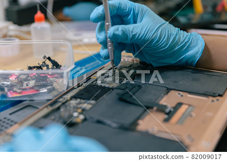 Phone repair concept a young electrical technician using a screwdriver to fasten the parts of an electronic device Phone repair concept a young electrical technician using a screwdriver to fasten the parts of an electronic device 82009017