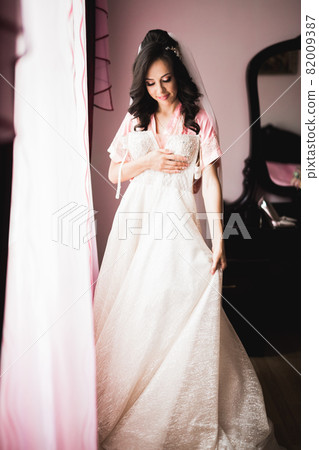 Beautiful bride wearing fashion wedding dress with feathers with luxury delight make-up and hairstyle, studio indoor photo shoot Beautiful bride wearing fashion wedding dress with feathers with luxury delight make-up and hairstyle, studio indoor photo shoot 82009387