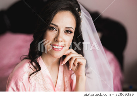 Beautiful bride wearing fashion wedding dress with feathers with luxury delight make-up and hairstyle, studio indoor photo shoot Beautiful bride wearing fashion wedding dress with feathers with luxury delight make-up and hairstyle, studio indoor photo shoot 82009389