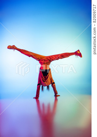 Young sportive girl dancing break dance alone isolated on colorful background at dance hall in neon light. Youth culture, movement, style and fashion, action. 82009717