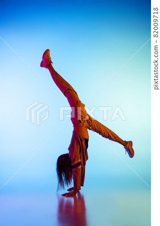 Young sportive girl dancing break dance alone isolated on colorful background at dance hall in neon light. Youth culture, movement, style and fashion, action. 82009718