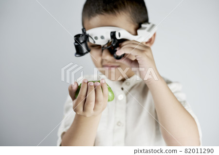 Little boy holding a slime and looking on it through the special magnifying eyeglasses headset 82011290