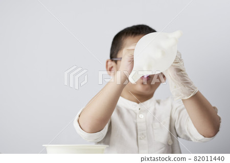 A little kid blowing medical gloves as balloon against the white background A little kid blowing medical gloves as balloon against the white background 82011440