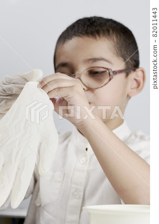 Little scientist kid wearing protective glove before his chemistry experiments with liquids Little scientist kid wearing protective glove before his chemistry experiments with liquids 82011443