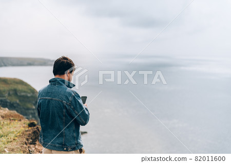 Man is standing on edge of the cliff on Irish sea 82011600