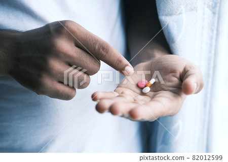 man's hand with medicine spilled out of the pill container man's hand with medicine spilled out of the pill container 82012599