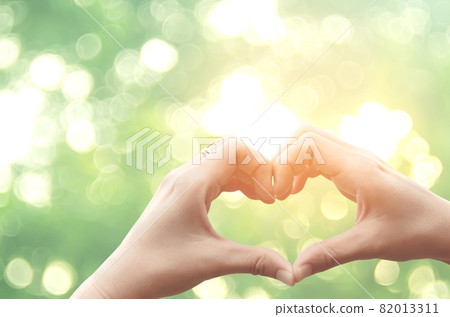 Female hands heart shape on nature green bokeh sun light flare and blur leaf abstract background. 82013311