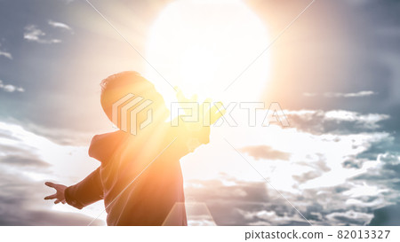 Freedom and feel good concept. Copy space of silhouette man rising hands on sunset sky background. 82013327