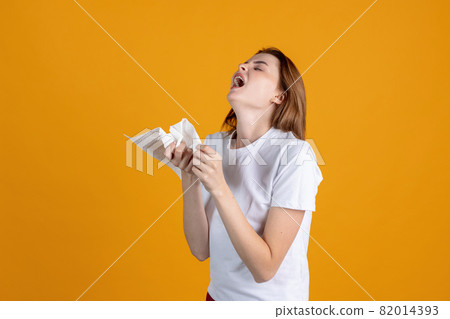 One young girl sneezing, having a runnynose isolated on yellow color studio background. Concept of human emotions, facial expression, health and medicine 82014393