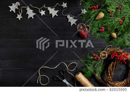Make a Christmas wreath with your own hands. Spruce branch, Christmas wreath and gifts on a black wooden background 82015095