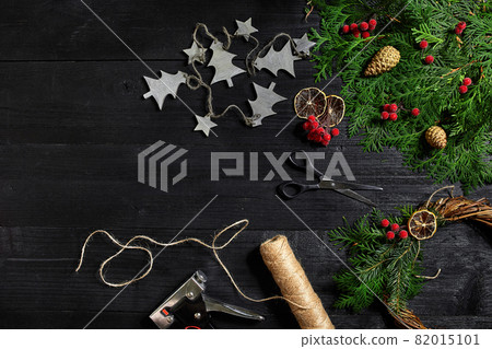 Make a Christmas wreath with your own hands. Spruce branch, Christmas wreath and gifts on a black wooden background 82015101